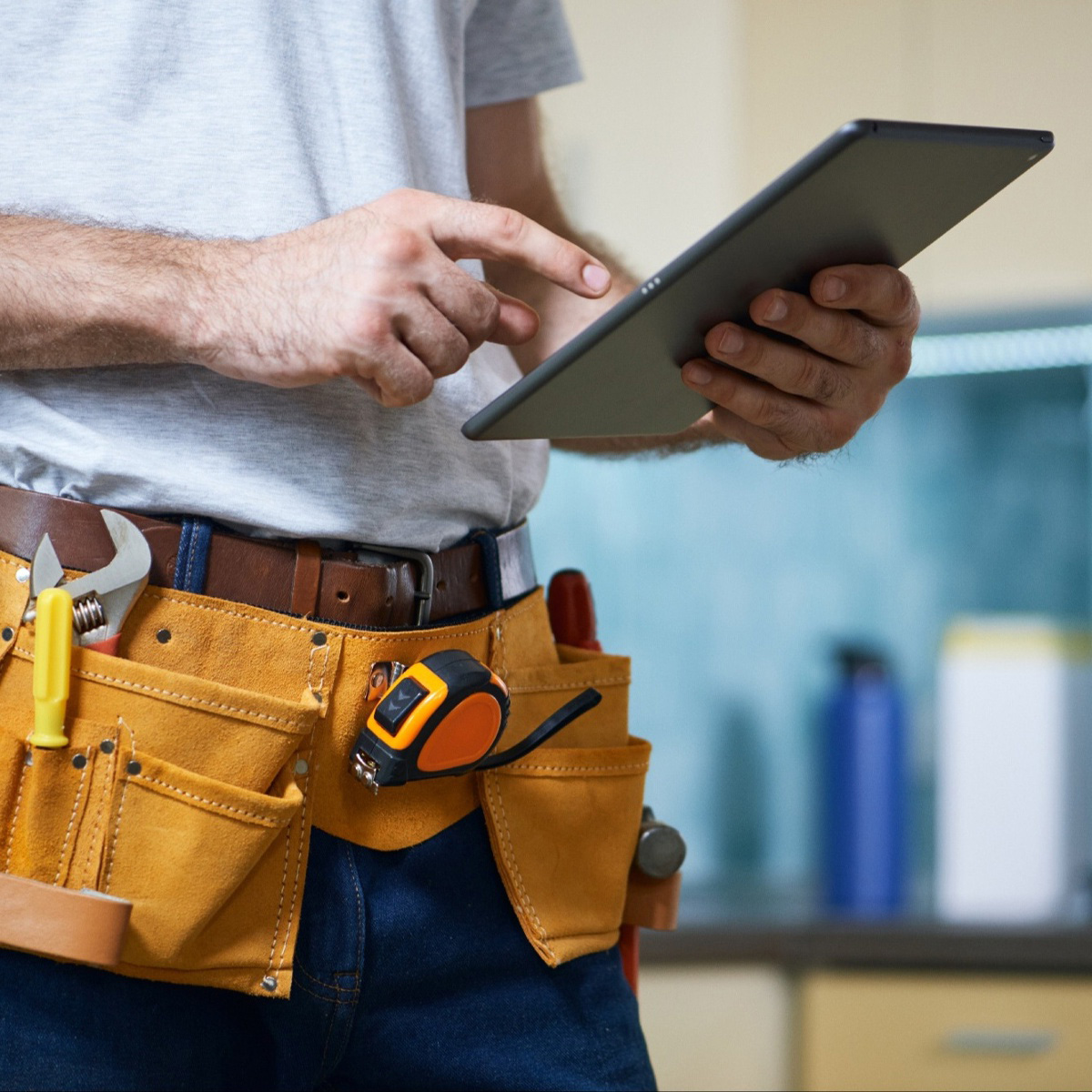 repairman-wearing-tool-belt-using-mobile-tablet-crop
